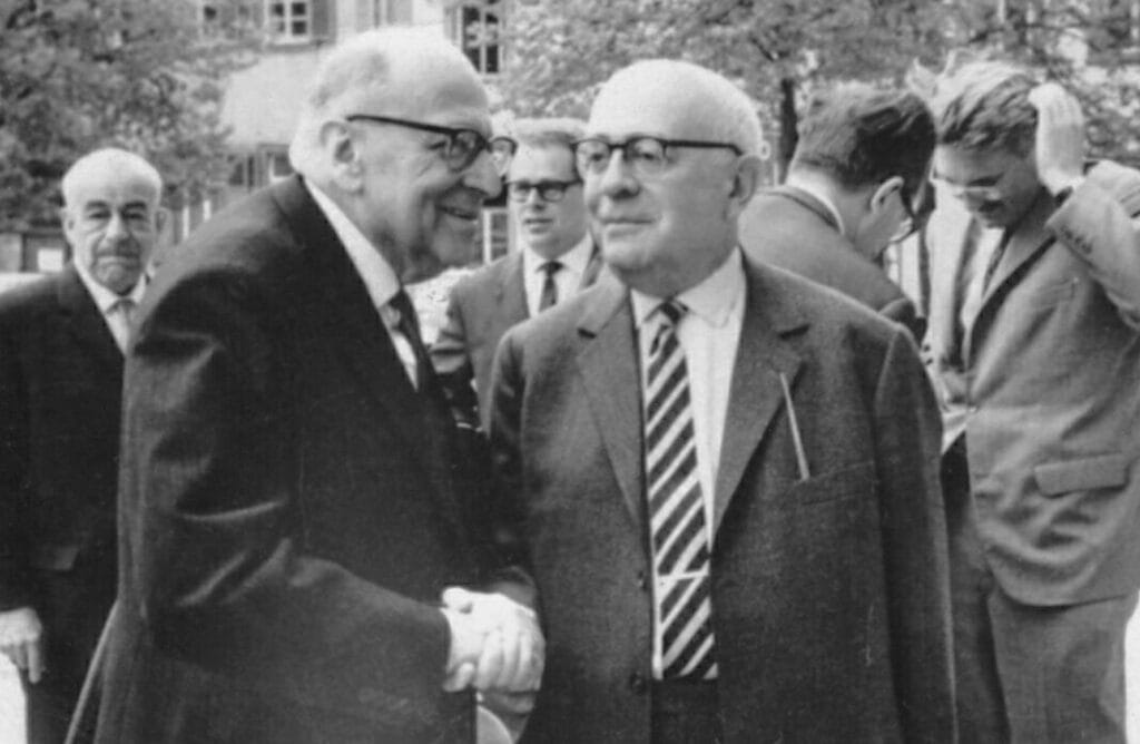 A black-and-white photo of Horkheimer and Adorno shaking hands.