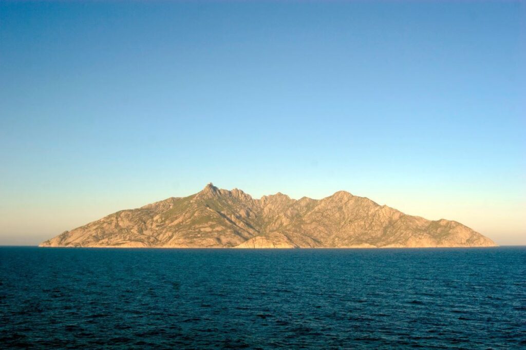 A photo of the rocky island of Monte Cristo, surrounded by the Mediterrean Sea.