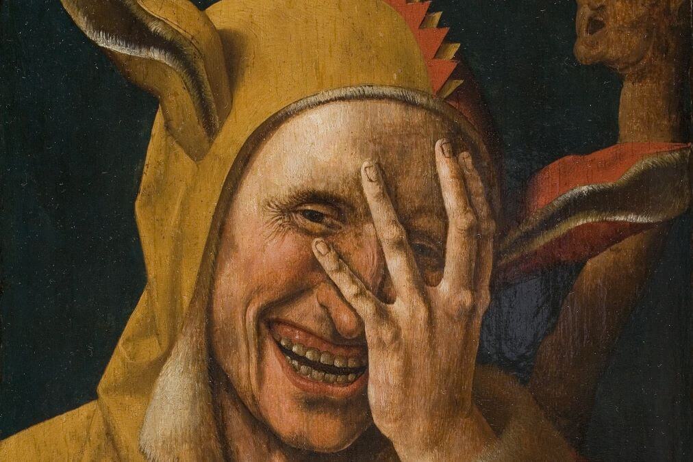 A Renaissance painting of a smiling jester in his typical colourful outfit.